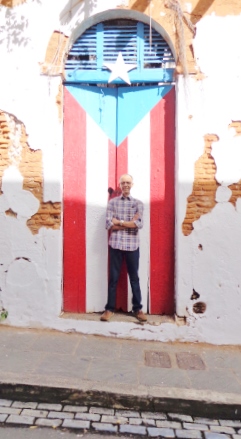 HECTOR ENTRE LA SOMBRA DEL VIEJO SAN JUAN Y UNA BANDERA ILUMINADA